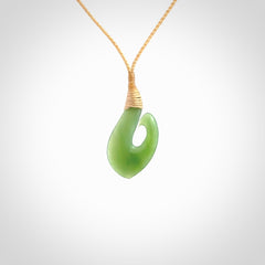 New Zealand jade hei-mate pendant. Hand carved in bright green jade by Ric Moor. The pendant is suspended from a beige plaited cord and is finished in a satin matte polish.