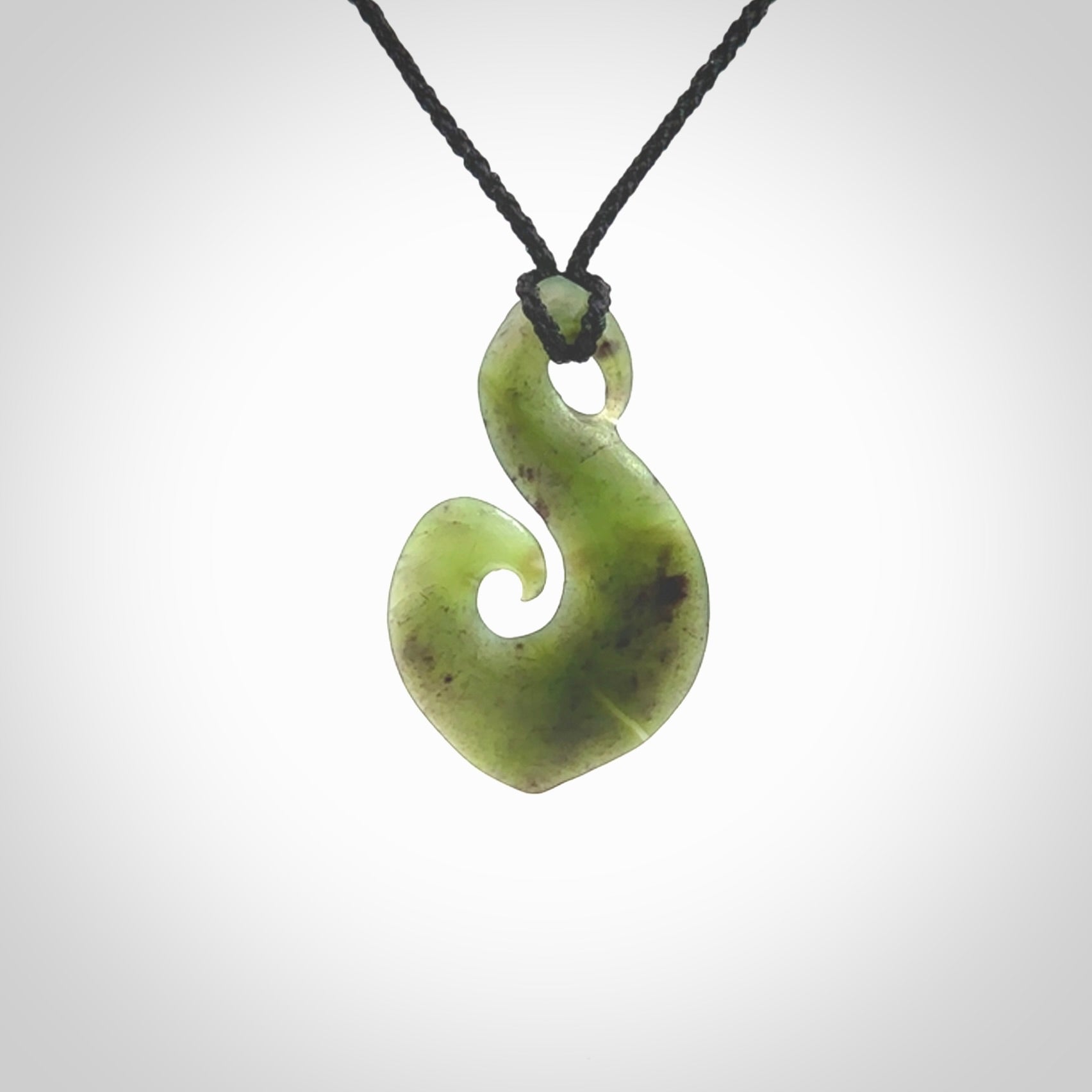 This koru/matau, is carved from a very striking New Zealand jade. It is both intricate and simple in design - it has hidden folds and smooth curves. A piece to be worn, the carving and the jade are both magnificent.