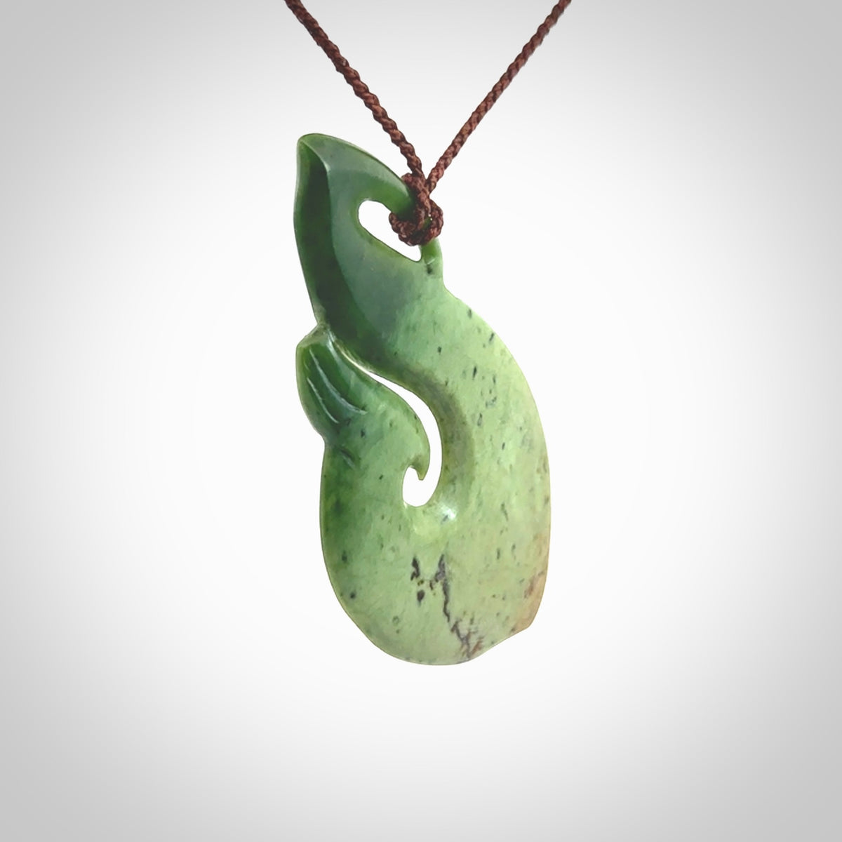 This matau, is a large pendant hand carved from New Zealand jade. It is both intricate and contemporary in design - it has hidden folds and smooth curves. A piece to be worn, the carving and the jade are both magnificent. A large hand carved New Zealand Jade hook by artist Ric Moor.