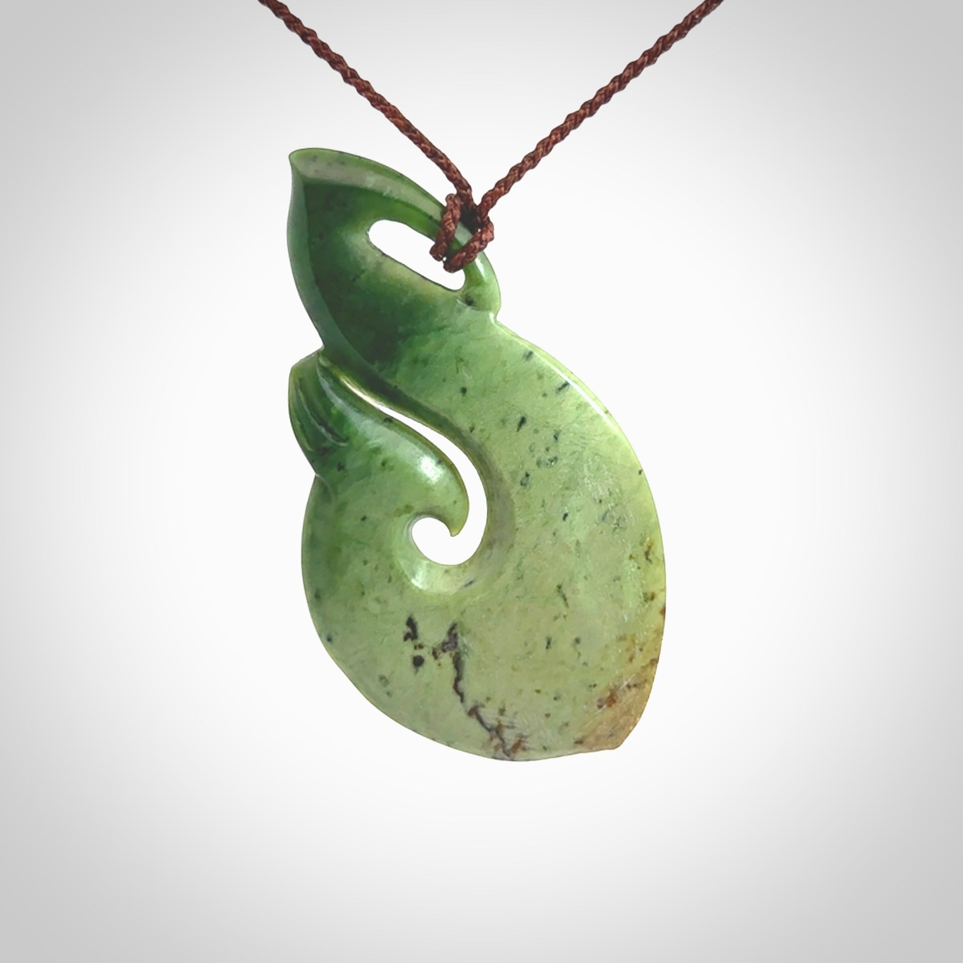 This matau, is a large pendant hand carved from New Zealand jade. It is both intricate and contemporary in design - it has hidden folds and smooth curves. A piece to be worn, the carving and the jade are both magnificent. A large hand carved New Zealand Jade hook by artist Ric Moor.