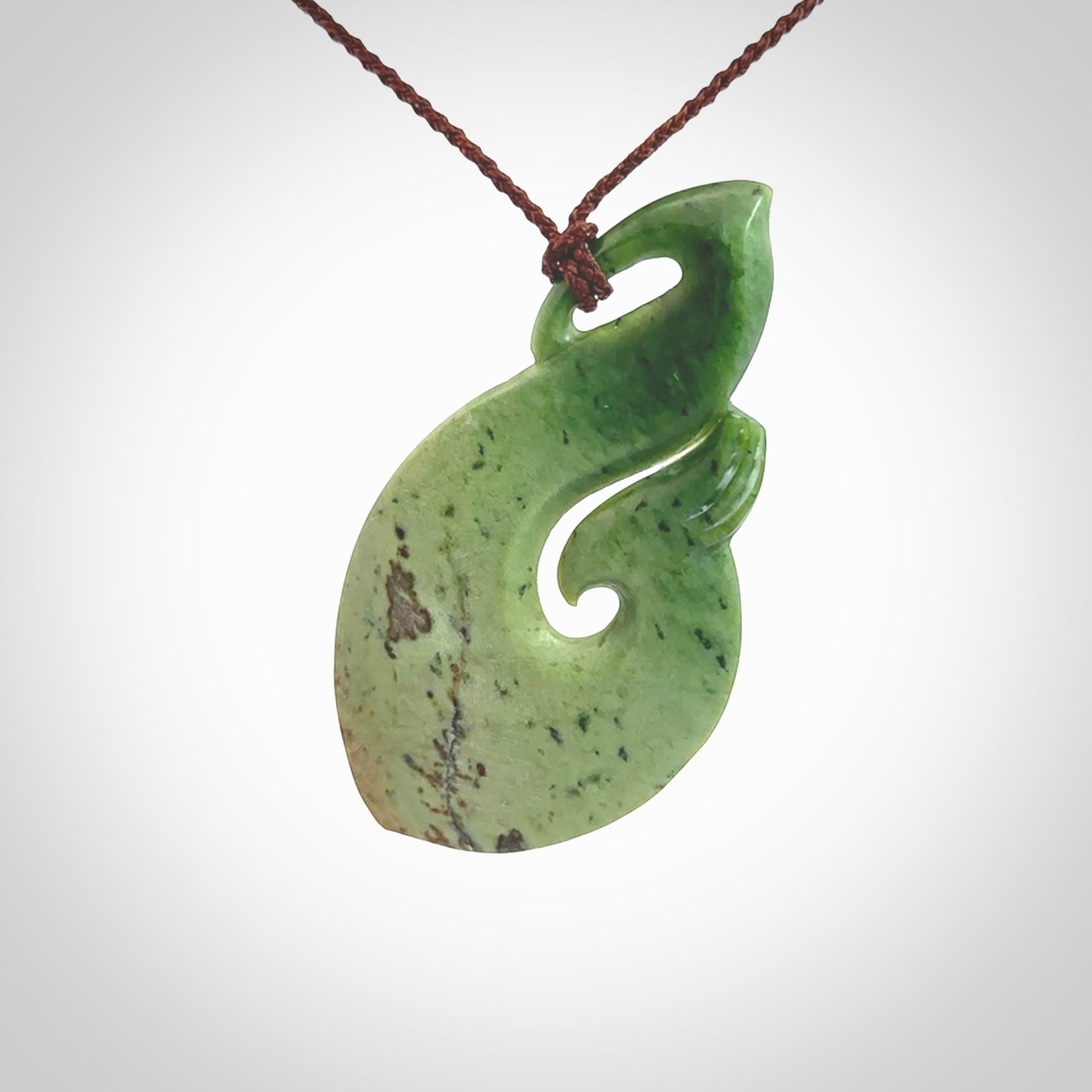 This matau, is a large pendant hand carved from New Zealand jade. It is both intricate and contemporary in design - it has hidden folds and smooth curves. A piece to be worn, the carving and the jade are both magnificent. A large hand carved New Zealand Jade hook by artist Ric Moor.