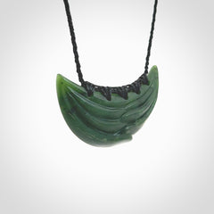 This picture shows a hand carved jade contemporary half-shield pendant. It is a deep green colour. This is a wonderful piece of jewellery. The cord is hand plaited and adjustable so that you can position the pendant where it suits you best. This piece was carved for us by Ric Moor. Delivery is free worldwide.