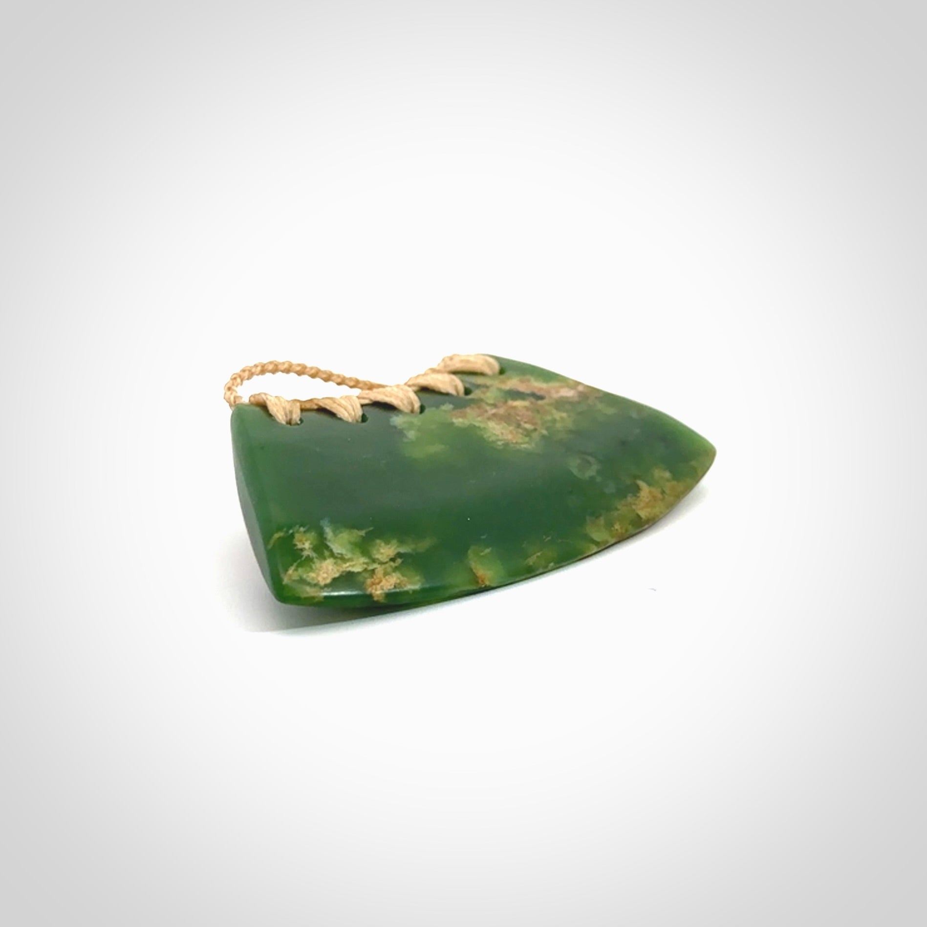 This picture shows a hand carved jade contemporary half-shield pendant. It is a deep green colour with orange and lighter shades of green throughout. This is a wonderful piece of jewellery. The cord is hand plaited and adjustable so that you can position the pendant where it suits you best. This piece was carved for us by Ric Moor. Delivery is free worldwide.