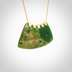 This picture shows a hand carved jade contemporary half-shield pendant. It is a deep green colour with orange and lighter shades of green throughout. This is a wonderful piece of jewellery. The cord is hand plaited and adjustable so that you can position the pendant where it suits you best. This piece was carved for us by Ric Moor. Delivery is free worldwide.