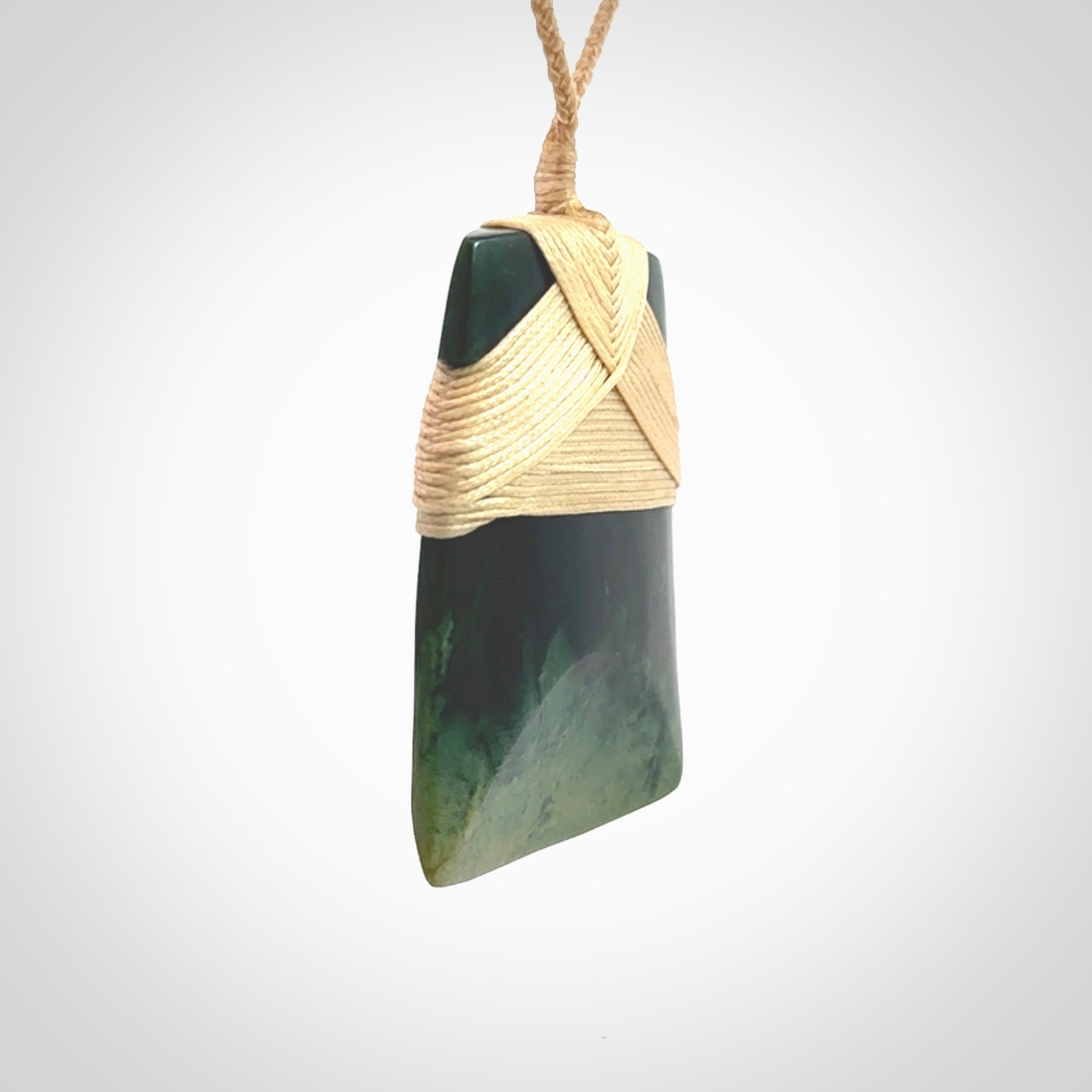 Hand carved from a lovely piece of local New Zealand Jade, a large and chunky Toki pendant. The quality of the workmanship and design is outstanding - this is a piece you will want to wear all the time. We have suspended this from a 4-plait beige cord which can be adjusted with a couple of slip knots and beige binding.