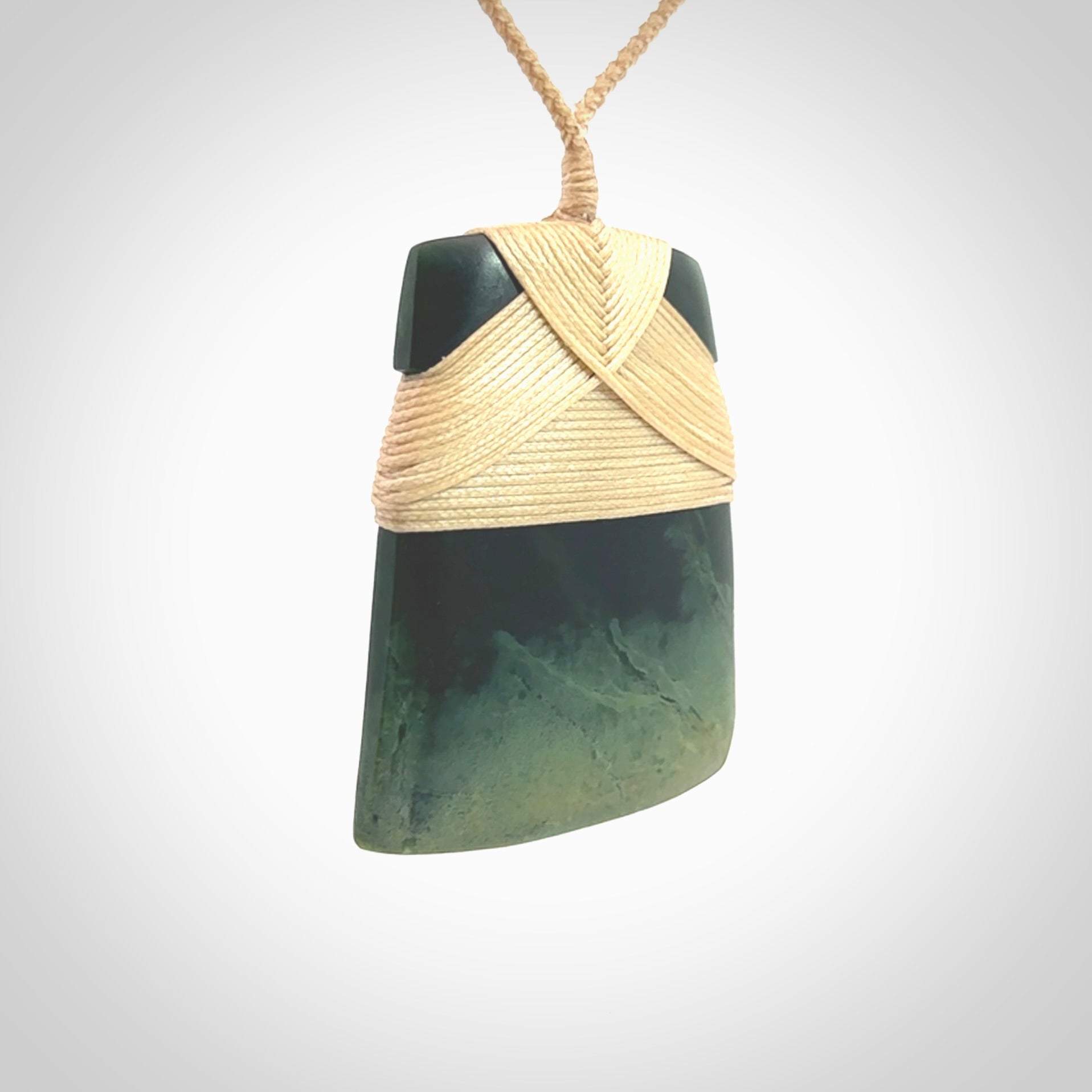 Hand carved from a lovely piece of local New Zealand Jade, a large and chunky Toki pendant. The quality of the workmanship and design is outstanding - this is a piece you will want to wear all the time. We have suspended this from a 4-plait beige cord which can be adjusted with a couple of slip knots and beige binding.