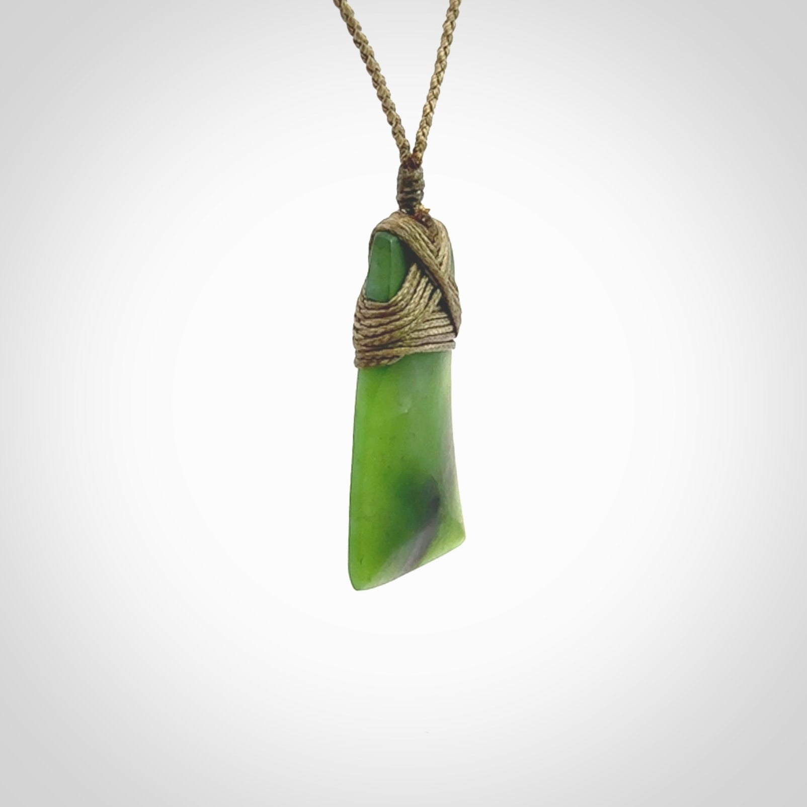 Toki pendant hand carved from a lovely piece of local New Zealand Jade. The quality of the workmanship and design is outstanding - this is a piece you will want to wear all the time. We have suspended this from a 3-plait khaki cord which can be adjusted with a couple of slip knots and beige binding.