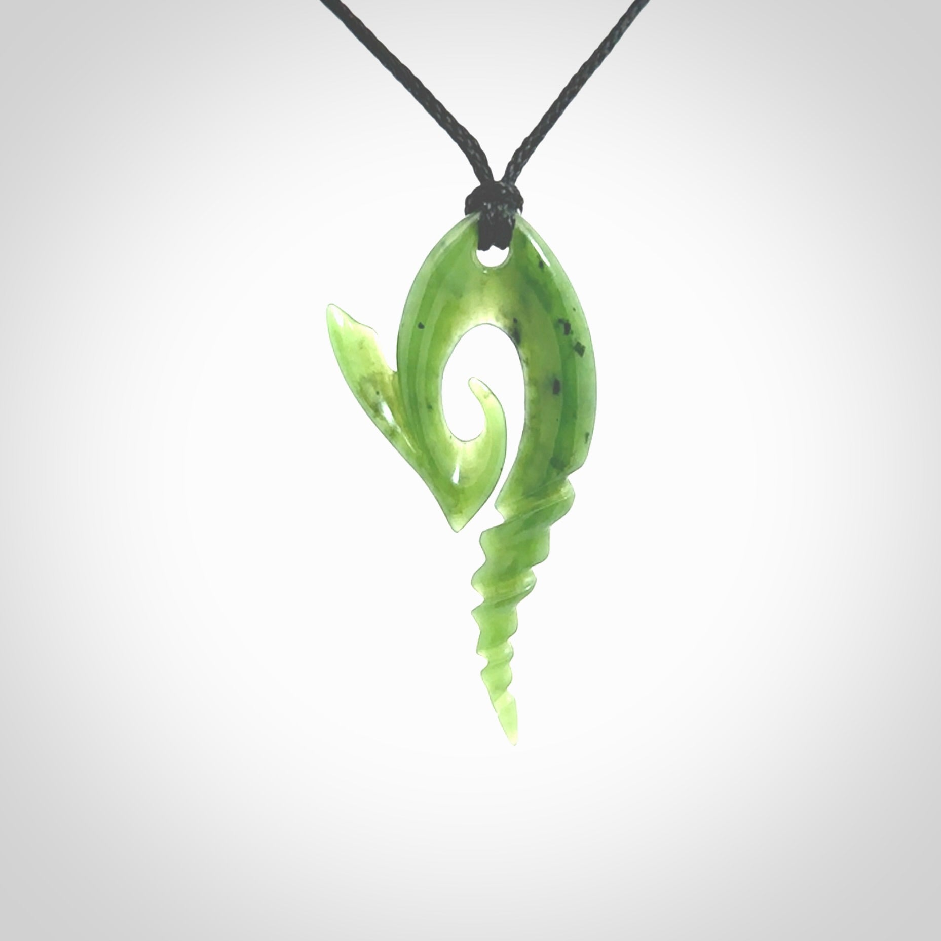 This photo shows a contemporary koru with whale tail pendant carved from New Zealand Jade. The artist, Shaun Gardiner, has carved this beautifully. We provide this piece with an adjustable Black cord. This is a fantastic work of art, we have one only.