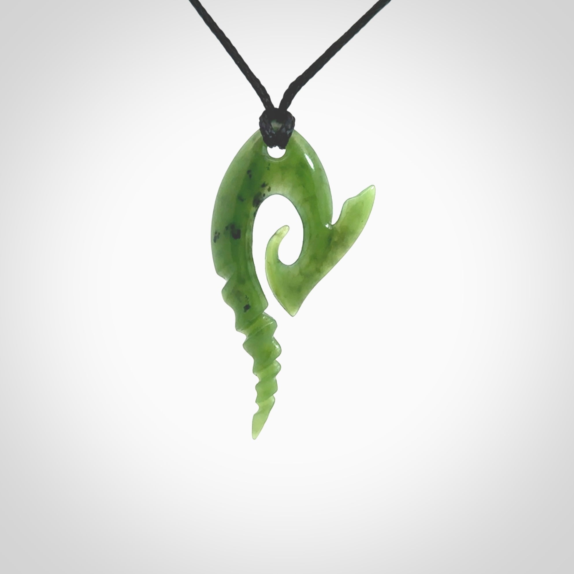 This photo shows a contemporary koru with whale tail pendant carved from New Zealand Jade. The artist, Shaun Gardiner, has carved this beautifully. We provide this piece with an adjustable Black cord. This is a fantastic work of art, we have one only.