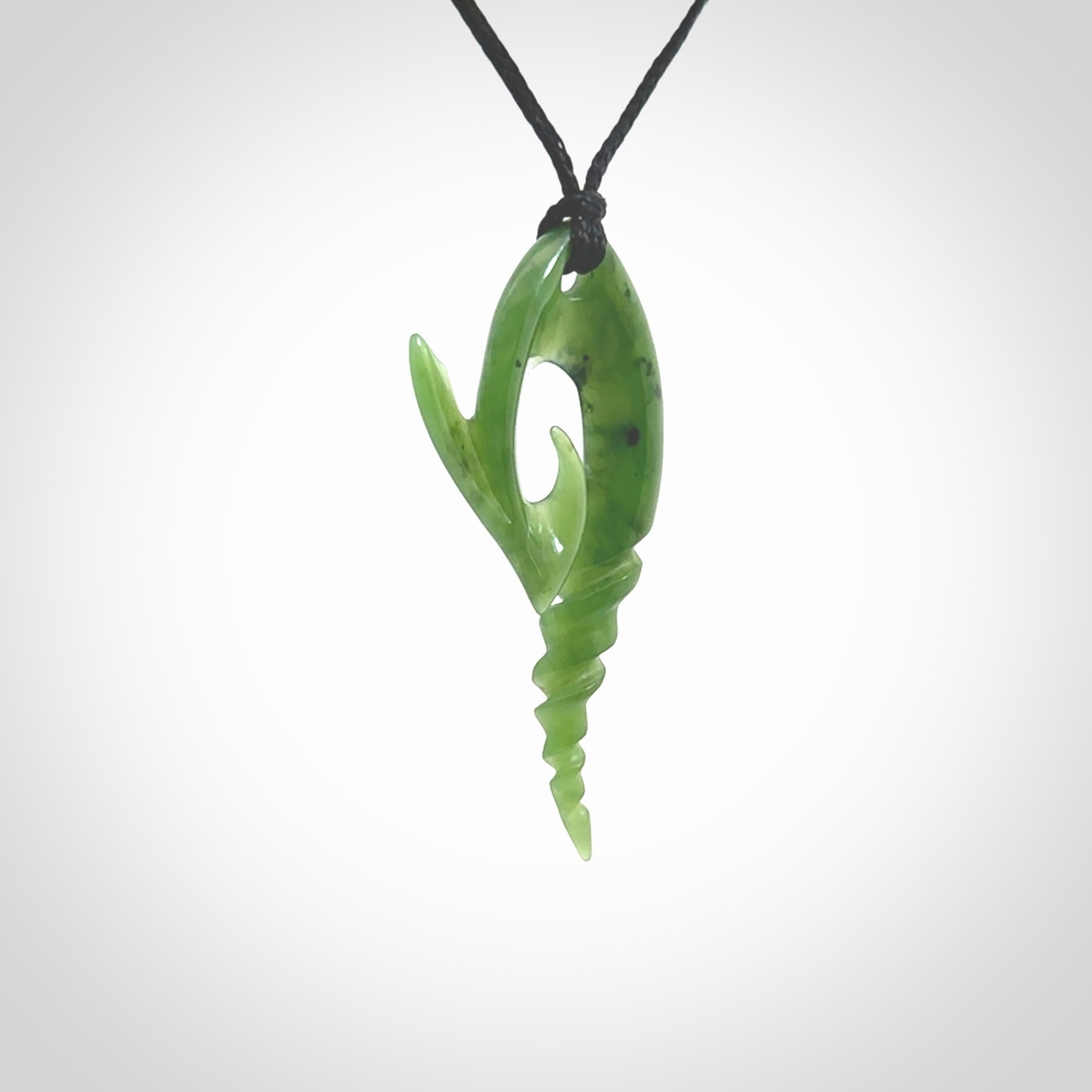 This photo shows a contemporary koru with whale tail pendant carved from New Zealand Jade. The artist, Shaun Gardiner, has carved this beautifully. We provide this piece with an adjustable Black cord. This is a fantastic work of art, we have one only.