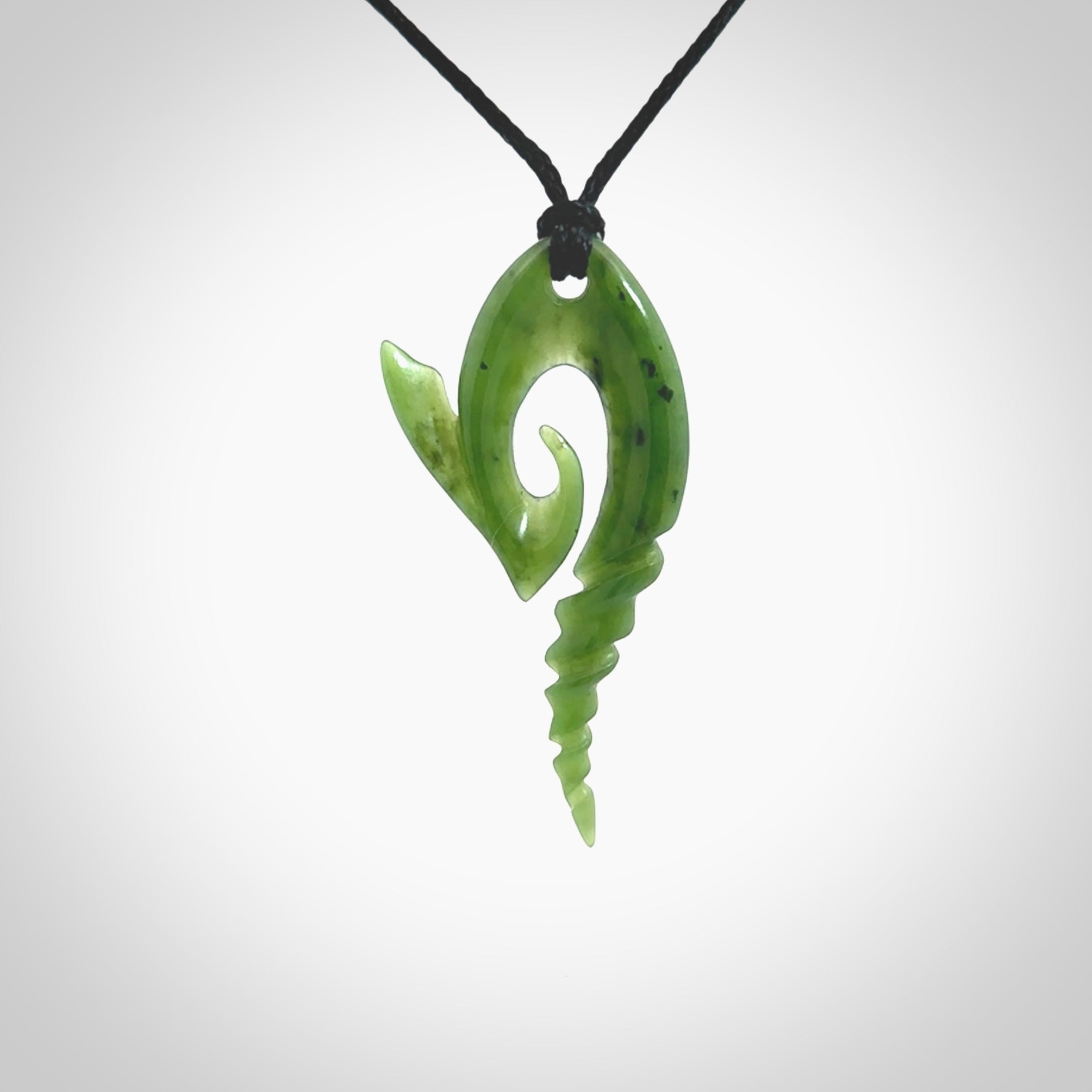 This photo shows a contemporary koru with whale tail pendant carved from New Zealand Jade. The artist, Shaun Gardiner, has carved this beautifully. We provide this piece with an adjustable Black cord. This is a fantastic work of art, we have one only.