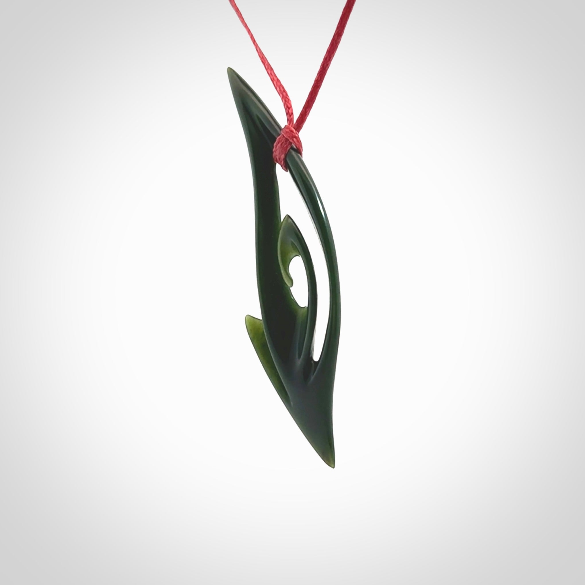 This photo shows a koru pendant carved from New Zealand Jade. The artist, Shaun Gardiner, has carved this beautifully. We provide this piece with an adjustable red cord. This is a fantastic work of art, we have one only.