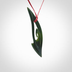 This photo shows a koru pendant carved from New Zealand Jade. The artist, Shaun Gardiner, has carved this beautifully. We provide this piece with an adjustable red cord. This is a fantastic work of art, we have one only.