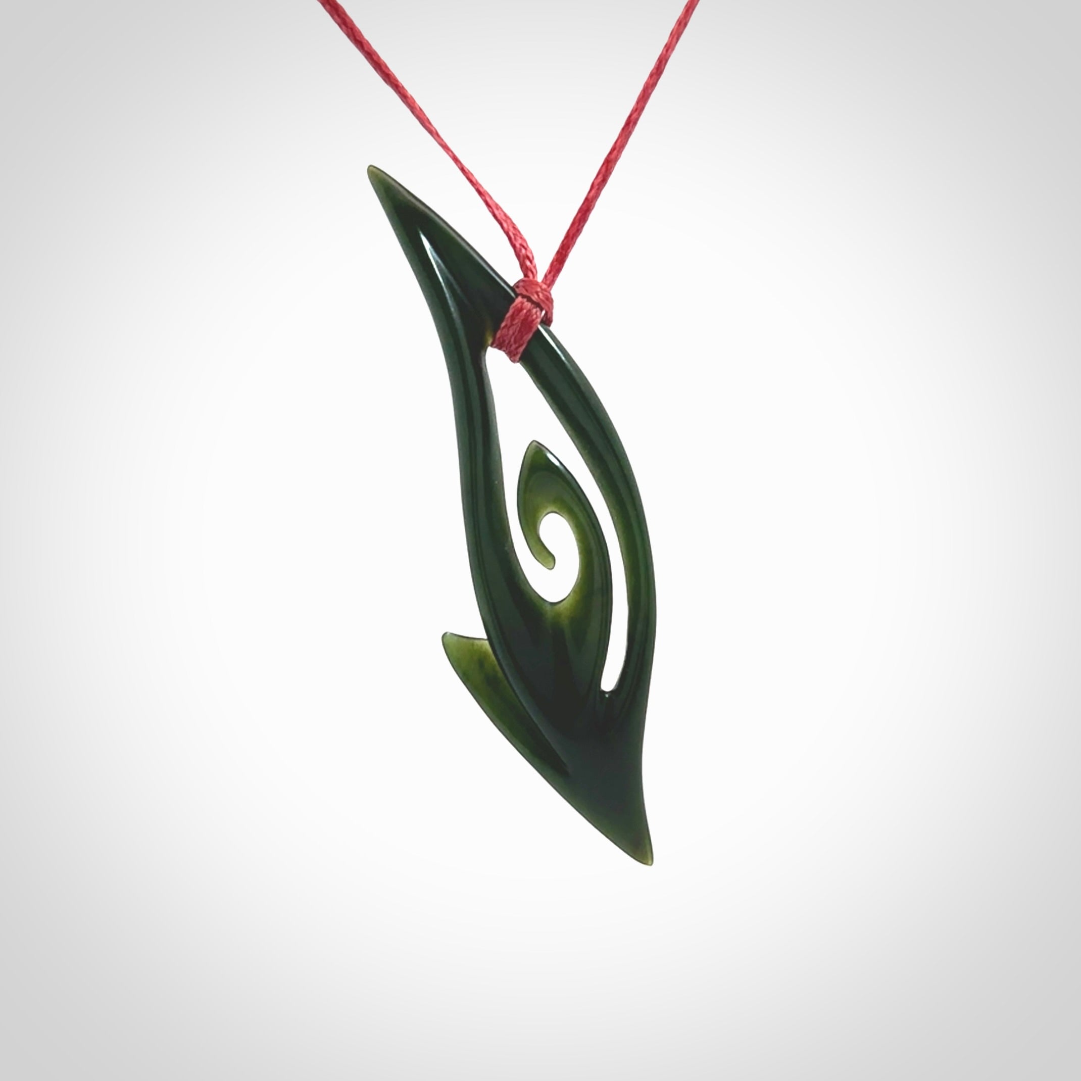 This photo shows a koru pendant carved from New Zealand Jade. The artist, Shaun Gardiner, has carved this beautifully. We provide this piece with an adjustable red cord. This is a fantastic work of art, we have one only.