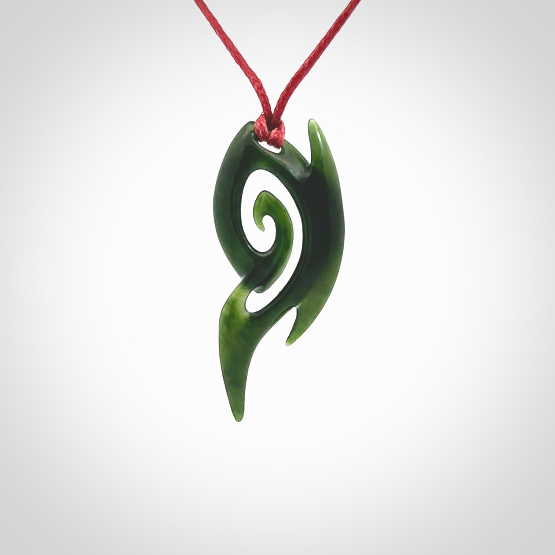 This photo shows a koru pendant carved from New Zealand Jade. The artist, Shaun Gardiner, has carved this beautifully. We provide this piece with an adjustable red cord. This is a fantastic work of art, we have one only.