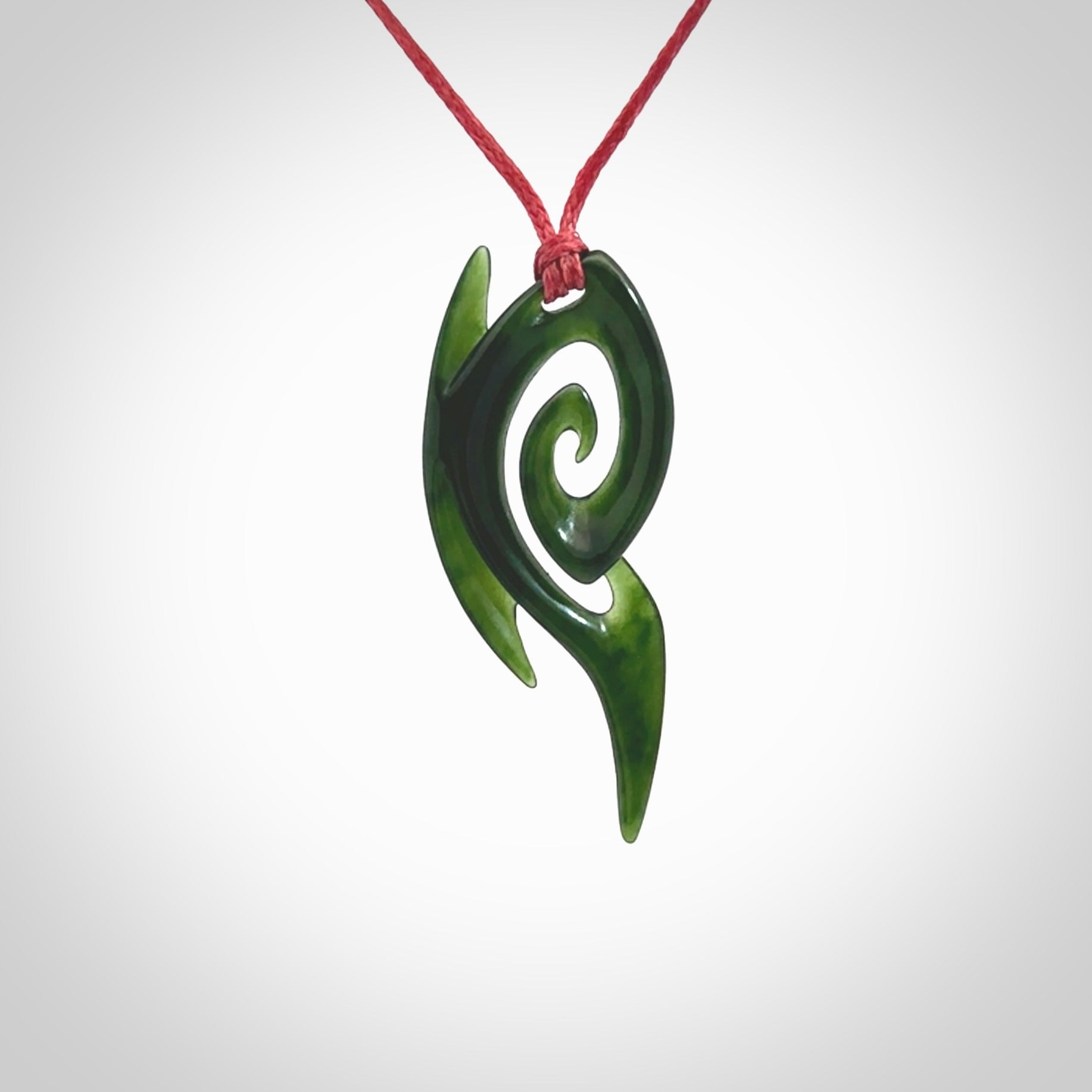 This photo shows a koru pendant carved from New Zealand Jade. The artist, Shaun Gardiner, has carved this beautifully. We provide this piece with an adjustable red cord. This is a fantastic work of art, we have one only.