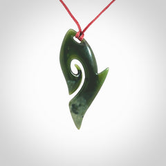 This photo shows a koru pendant carved from New Zealand Jade. The artist, Shaun Gardiner, has carved this beautifully. We provide this piece with an adjustable red cord. This is a fantastic work of art, we have one only.