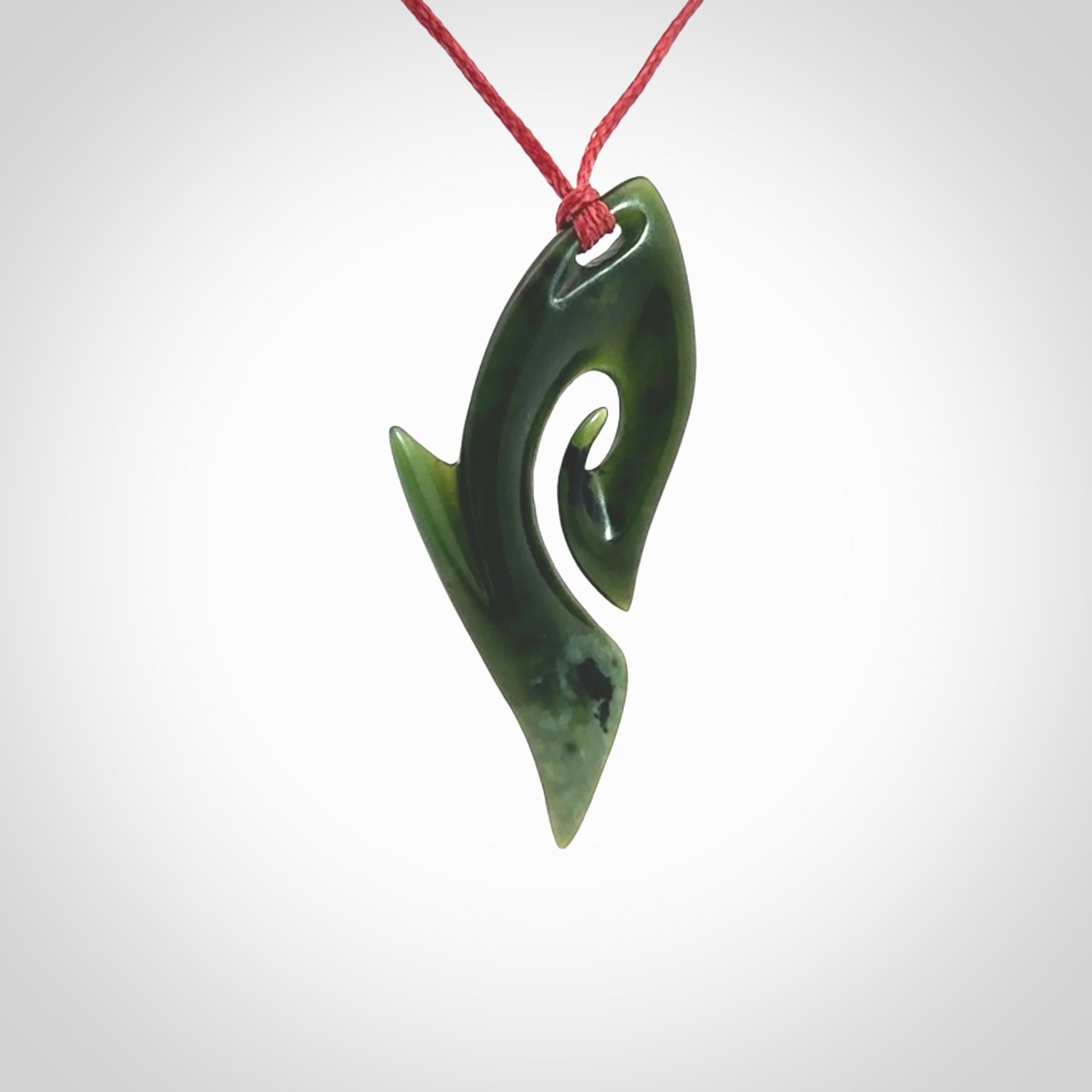 This photo shows a koru pendant carved from New Zealand Jade. The artist, Shaun Gardiner, has carved this beautifully. We provide this piece with an adjustable red cord. This is a fantastic work of art, we have one only.