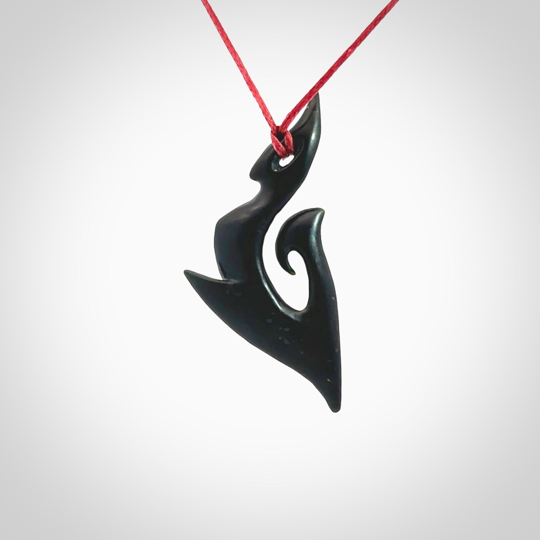 This photo shows a large contemporary koru pendant carved from New Zealand Jade. The artist, Shaun Gardiner, has carved this beautifully. We provide this piece with an adjustable red cord. This is a fantastic work of art, we have one only.