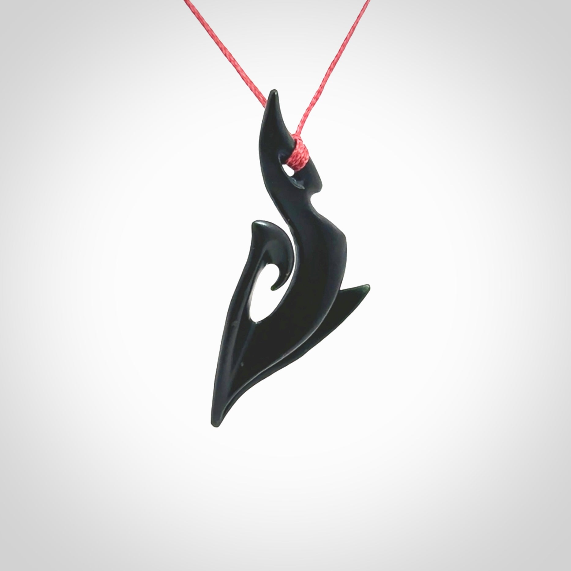 This photo shows a large contemporary koru pendant carved from New Zealand Jade. The artist, Shaun Gardiner, has carved this beautifully. We provide this piece with an adjustable red cord. This is a fantastic work of art, we have one only.