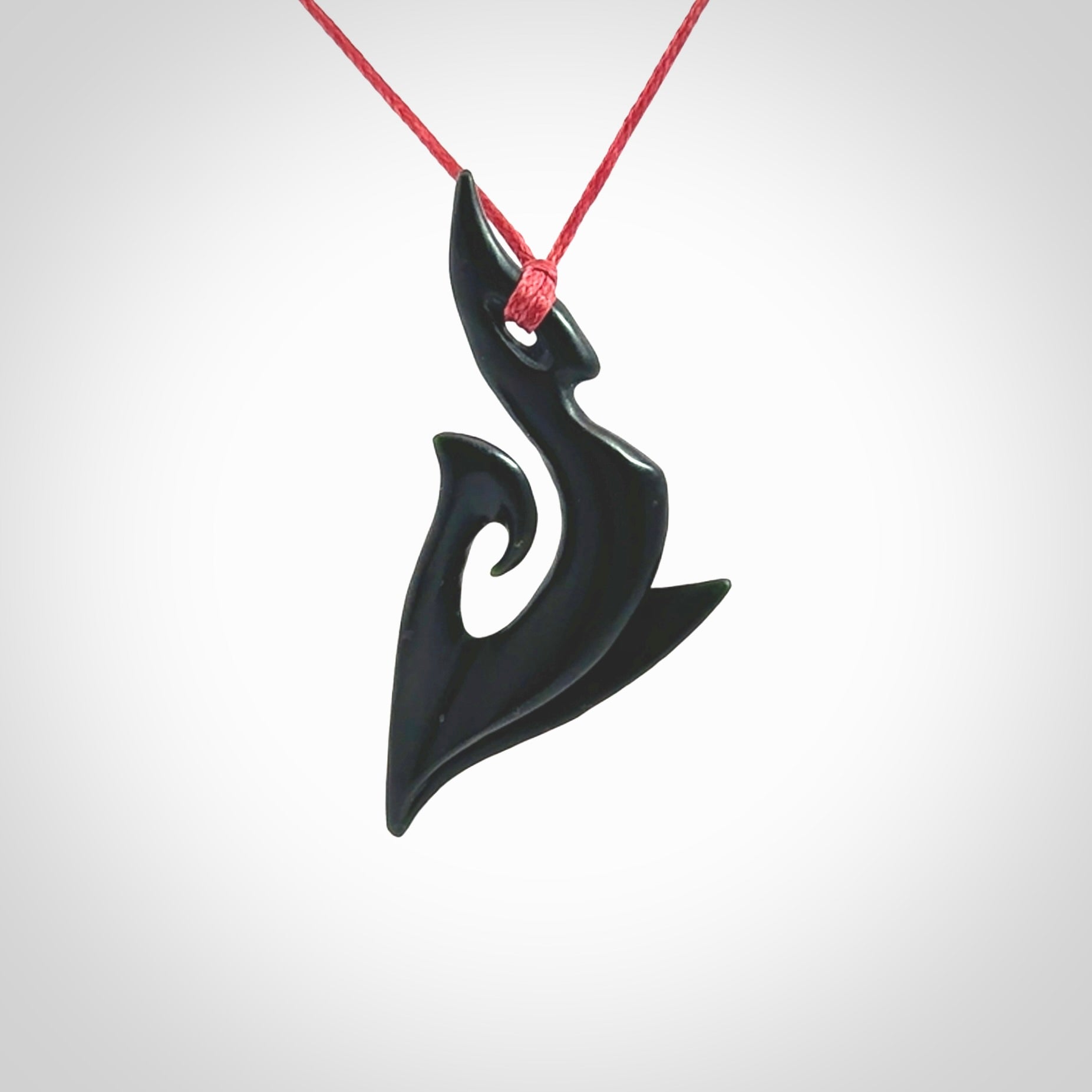 This photo shows a large contemporary koru pendant carved from New Zealand Jade. The artist, Shaun Gardiner, has carved this beautifully. We provide this piece with an adjustable red cord. This is a fantastic work of art, we have one only.