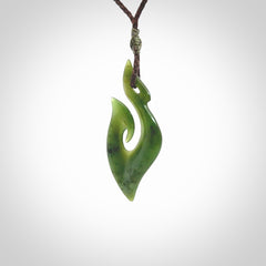 This photo shows a matau pendant carved from New Zealand Pounamu, Jade. The artist, Shaun Gardiner, has carved this beautifully. We provide this piece with an adjustable brown coloured cord. This is a fantastic work of art, we have one only.