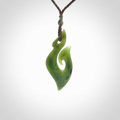 This photo shows a matau pendant carved from New Zealand Pounamu, Jade. The artist, Shaun Gardiner, has carved this beautifully. We provide this piece with an adjustable brown coloured cord. This is a fantastic work of art, we have one only.