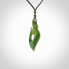 This photo shows a matau pendant carved from New Zealand Pounamu, Jade. The artist, Shaun Gardiner, has carved this beautifully. We provide this piece with an adjustable brown coloured cord. This is a fantastic work of art, we have one only.