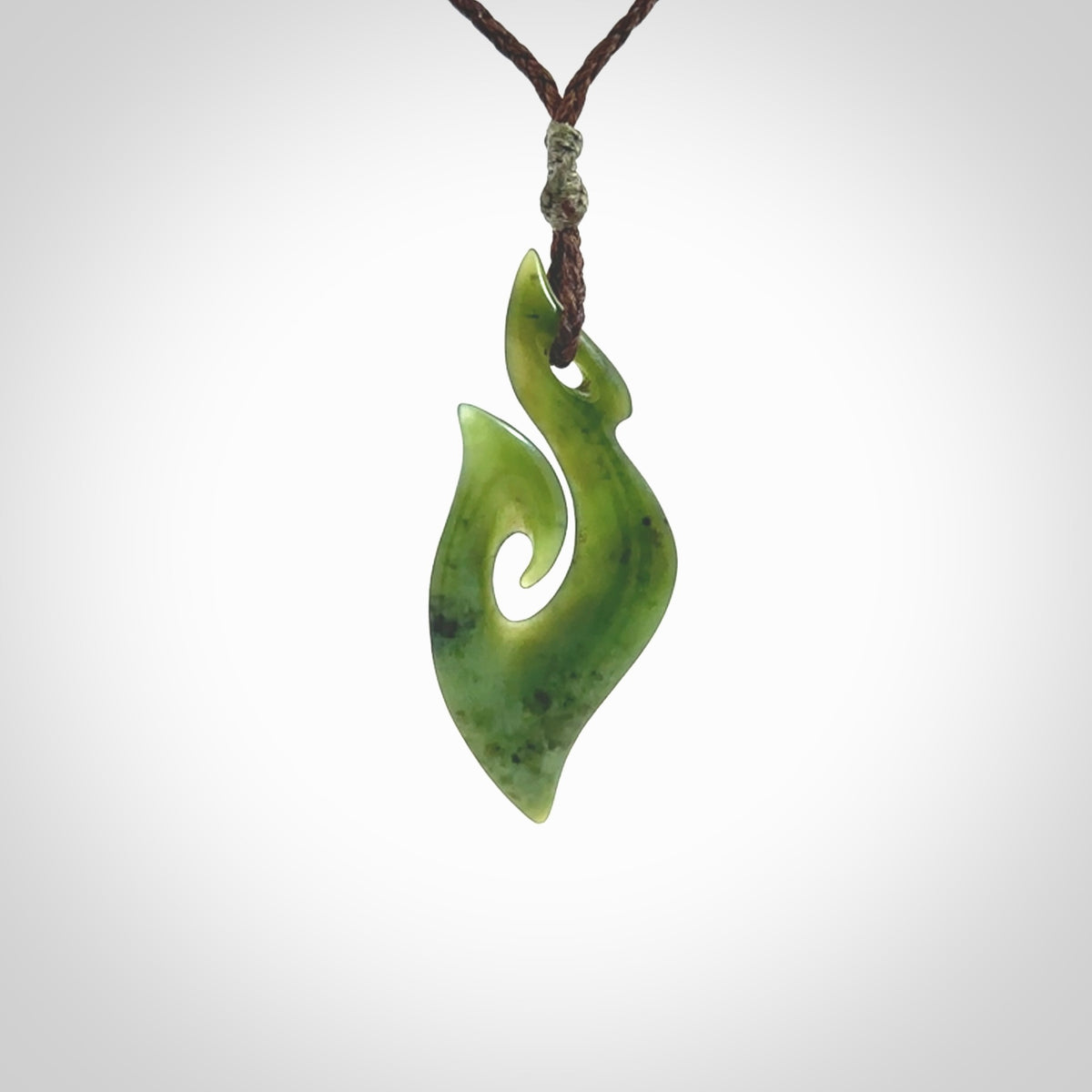 This photo shows a matau pendant carved from New Zealand Pounamu, Jade. The artist, Shaun Gardiner, has carved this beautifully. We provide this piece with an adjustable brown coloured cord. This is a fantastic work of art, we have one only.