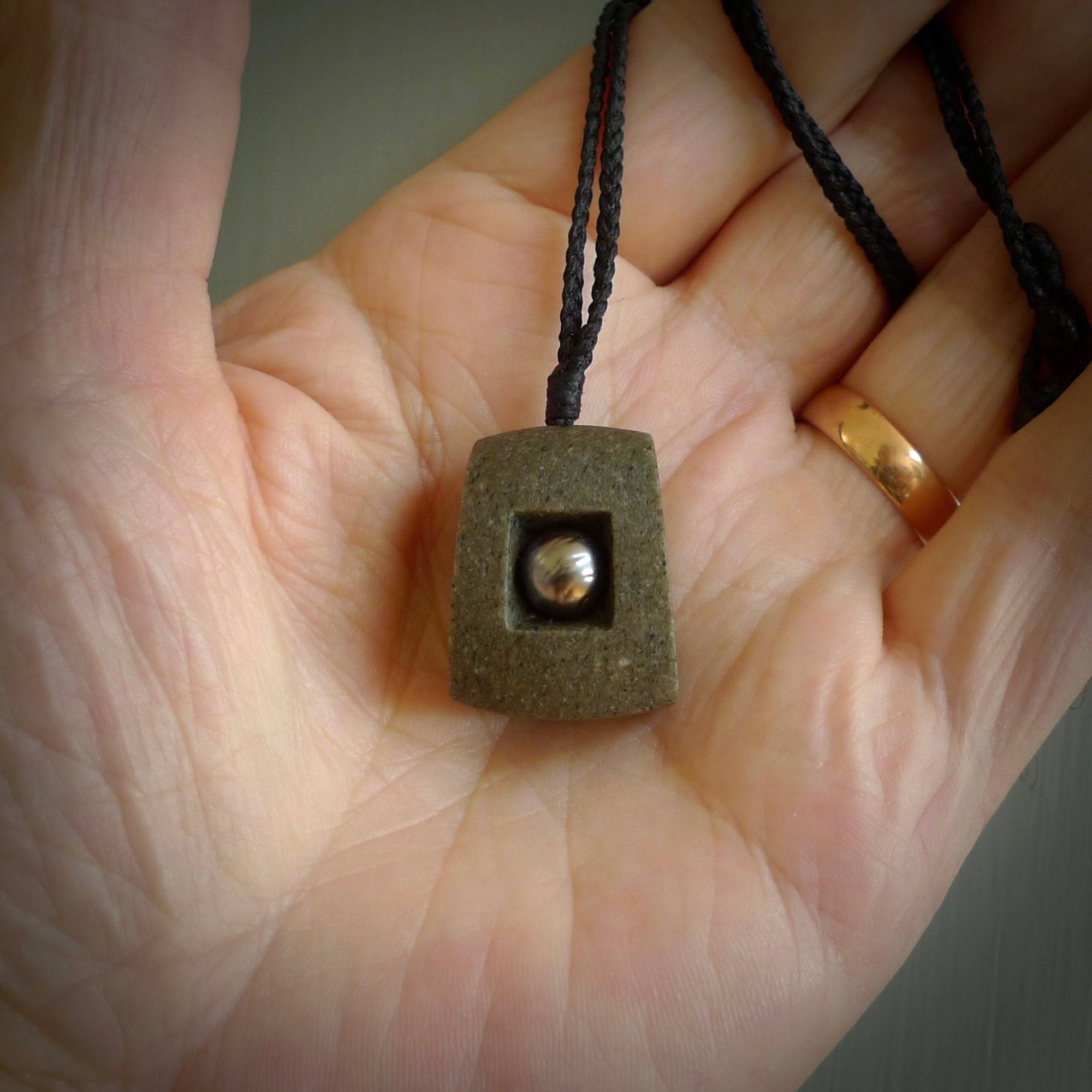 Greywacke stone pendant with Black Pearl insert. Hand carved by Rhys Hall for NZ Pacific. Handmade contemporary jewellery for sale online.