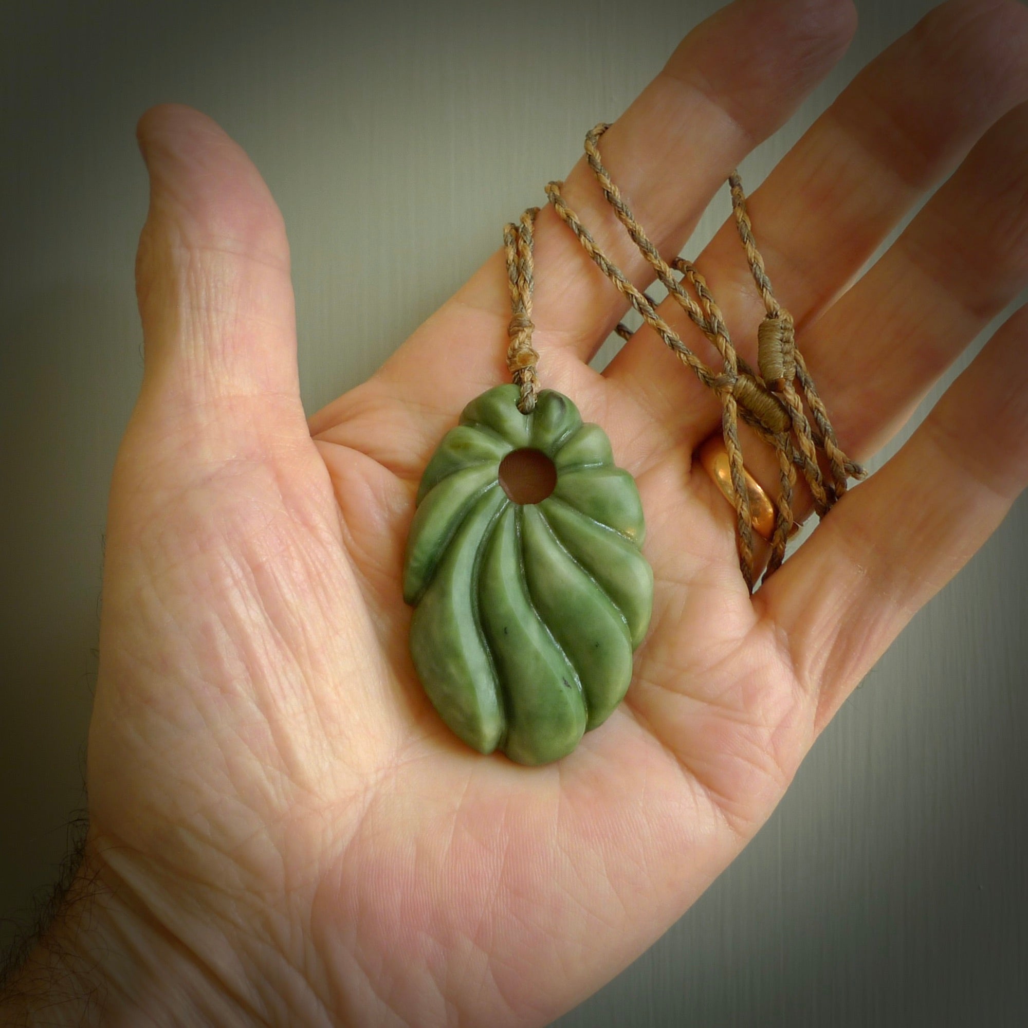 This picture shows a contemporary drop shaped pendant, hand carved from New Zealand flower jade. We will provide this with an adjustable plaited cord. Hand crafted stunning New Zealand Marsden Flower Jade drop pendant by Ana Krakosky.