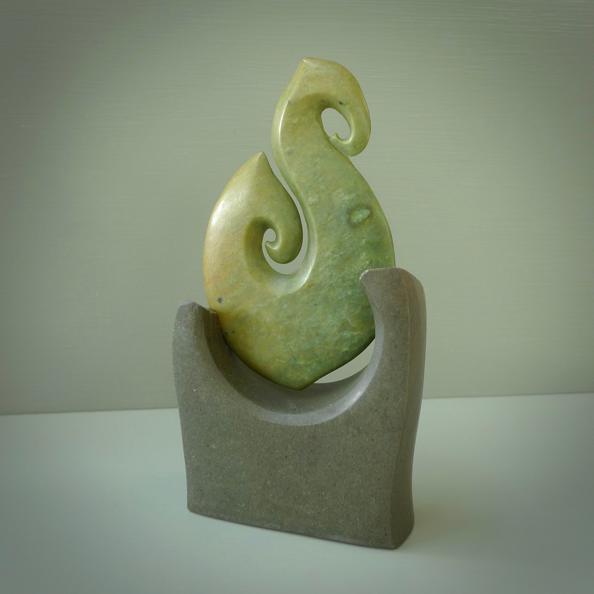 Hand carved New Zealand Flower Jade Hook with Greywacke stand sculpture. Hand carved in New Zealand by Ric Moor. This is a one only sculpture and is a beautiful, large, display piece.