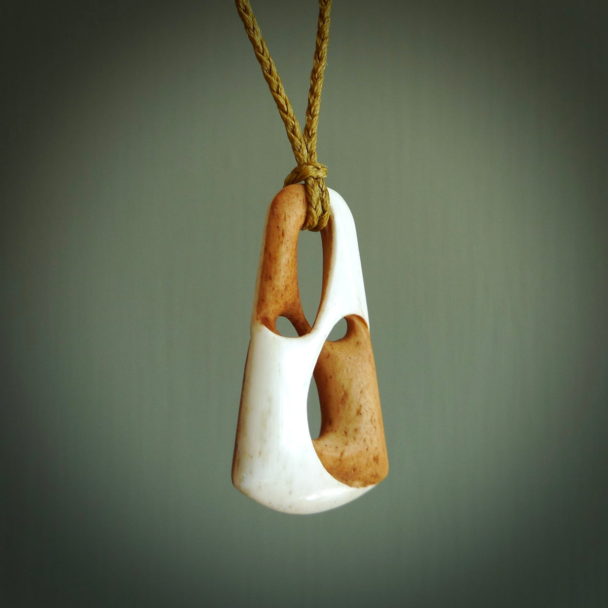 A hand carved bone contemporary, intricate, twist pendant. The cord is a tan colour and is adjustable. A medium sized hand made contemporary necklace by New Zealand artist Tonijae Brockway. Tonijae has stained parts of the bone which really add to the dimension of this pendant. One off work of art to wear.