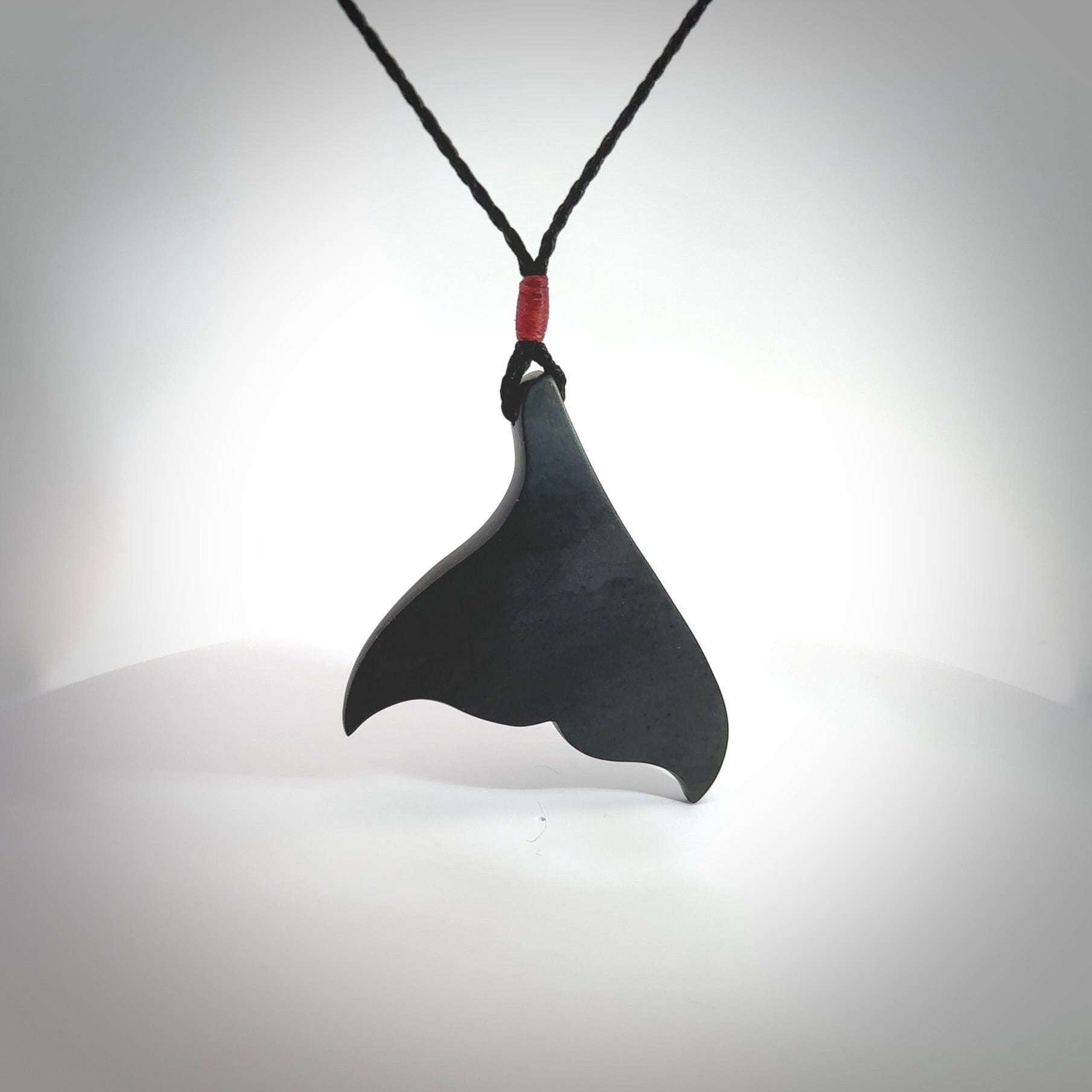 Hand carved New Zealand Argillite Stone whale tail pendant by Rueben Tipene. Hand made art to wear for lovers of the ocean. Delivered with express courier and delivered to you on an adjustable cord.