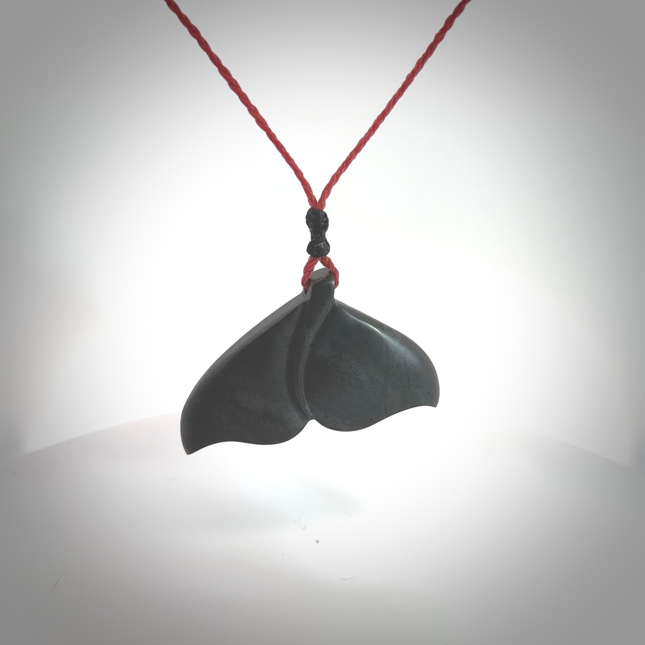 Hand carved New Zealand Argillite Stone whale tail pendant by Rueben Tipene. Hand made art to wear for lovers of the ocean. Delivered with express courier and delivered to you on an adjustable cord.