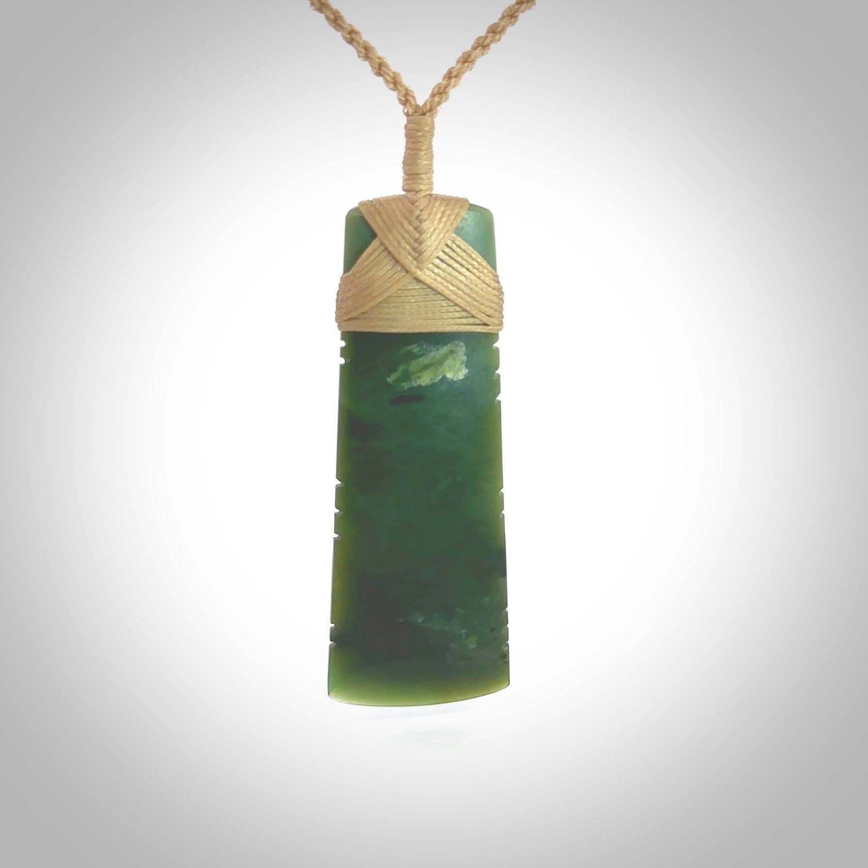 A large and beautiful hand carved toki pendant. This piece is carved from New Zealand jade by Jeromy Van Riel. This is a wonderful large toki bound with a hand-plaited cord and a traditional lashing. A beautiful, traditional toki for sale online.