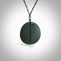 Greywacke stone pendant with New Zealand Jade Pounamu insert. Hand carved by Rhys Hall for NZ Pacific. Handmade jewellery for sale online. Delivered to you with express courier in one of our kete pouches.