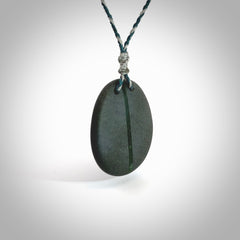 Greywacke stone pendant with New Zealand Jade Pounamu insert. Hand carved by Rhys Hall for NZ Pacific. Handmade jewellery for sale online. Delivered to you with express courier in one of our kete pouches.