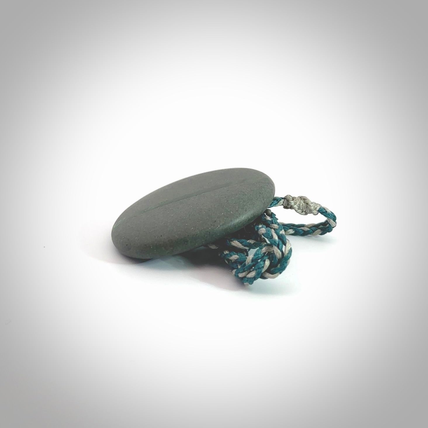 Greywacke stone pendant with New Zealand Jade Pounamu insert. Hand carved by Rhys Hall for NZ Pacific. Handmade jewellery for sale online. Delivered to you with express courier in one of our kete pouches.