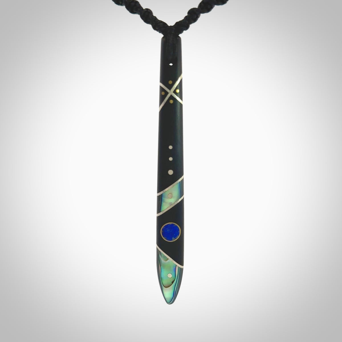 This photo shows a medium sized taiaha pendant hand carved from piano key with Afghani Lapis Lazuli and Chinese Glowing Stone, Sleeping Beauty Turquoise inlay alongside; brass and silver. This is a stand out one off necklace for those who appreciate art to wear. It is provided with a cord in black that is a fixed length with Paua Shell Toggle. We ship this piece worldwide and shipping is included in the price.