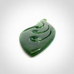 A beautiful large hand carved matau with koru pendant. Carved for us by Ross Crump from rare New Zealand jade. This is a wonderful pendant to gift to someone special.