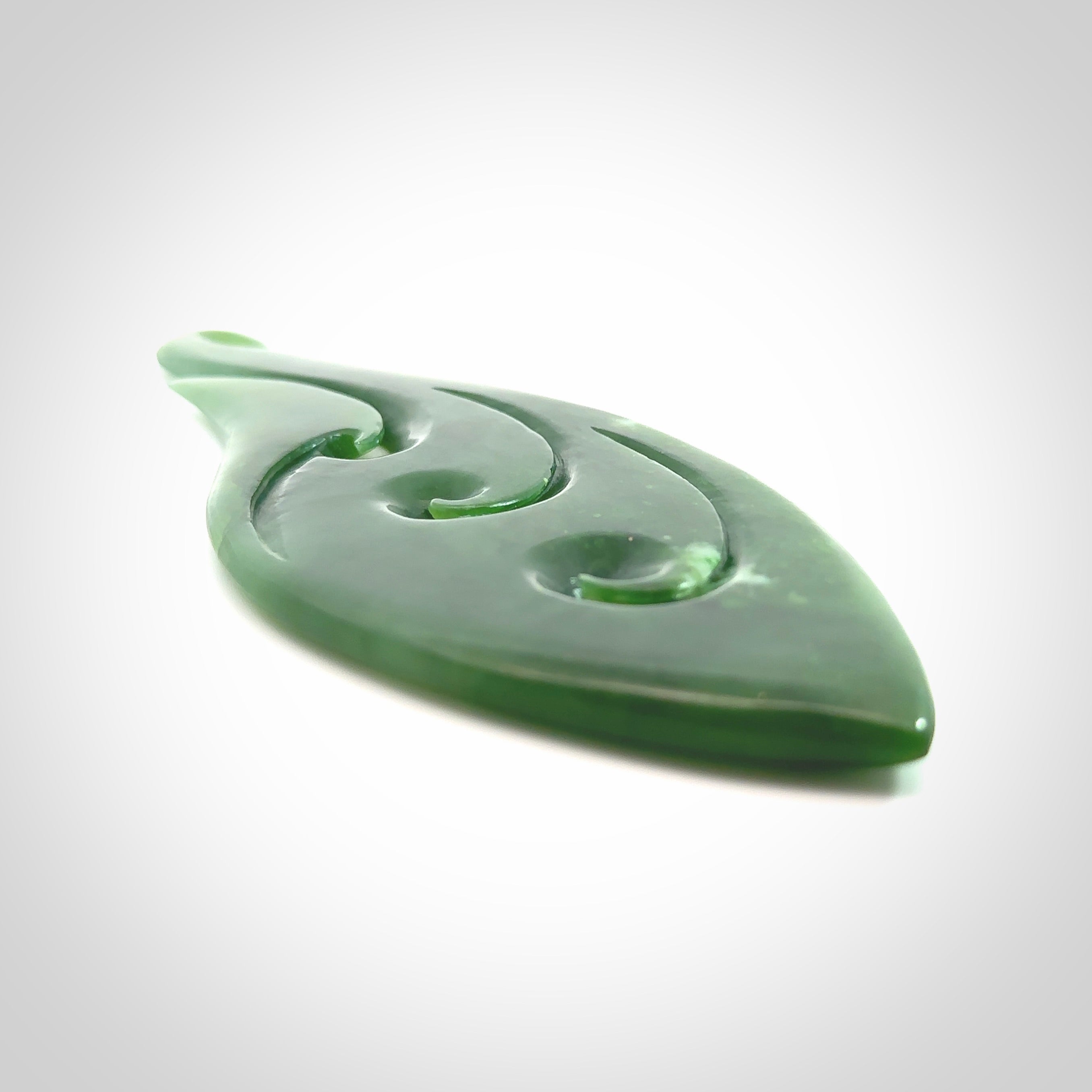 A beautiful large hand carved matau with koru pendant. Carved for us by Ross Crump from rare New Zealand jade. This is a wonderful pendant to gift to someone special.