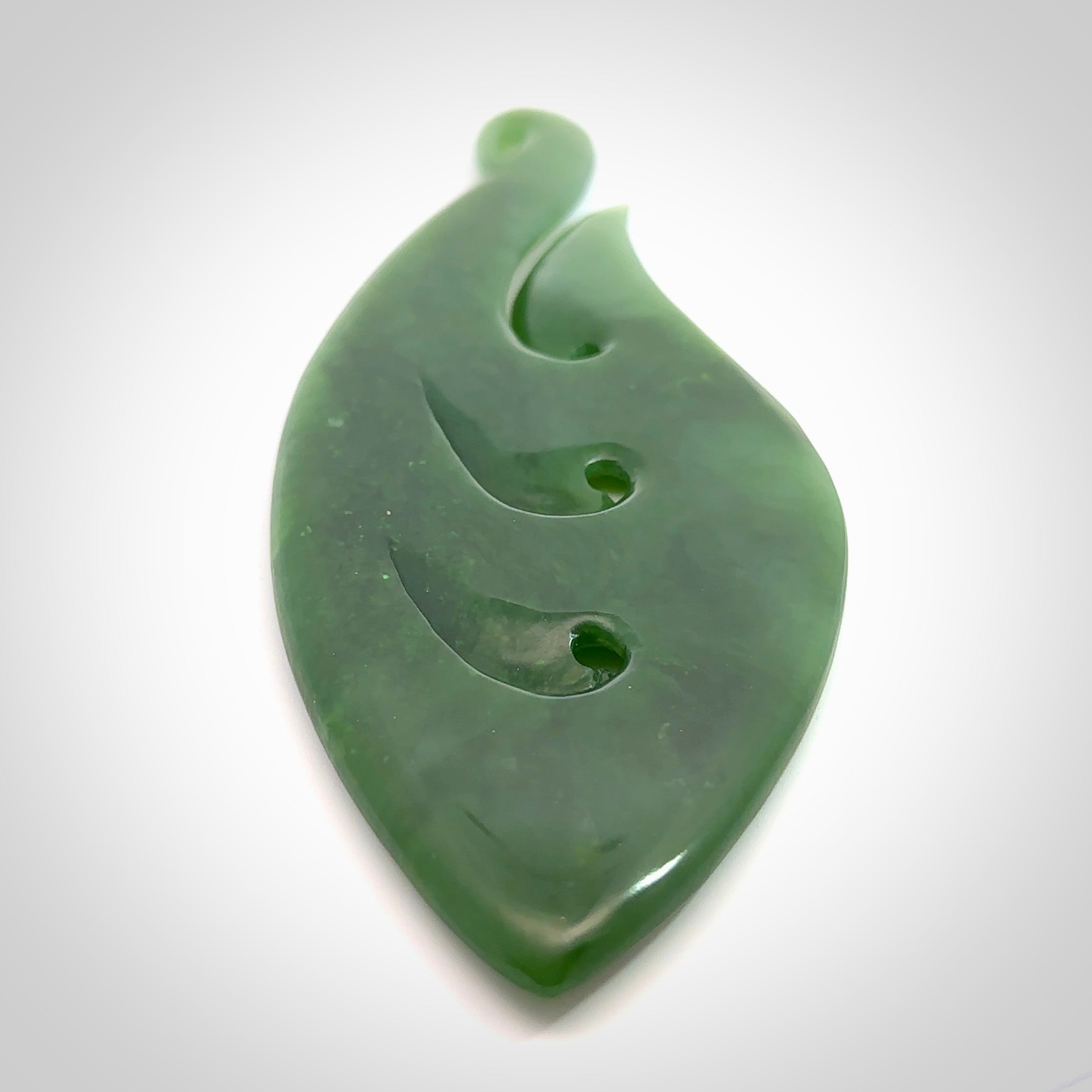 A beautiful large hand carved matau with koru pendant. Carved for us by Ross Crump from rare New Zealand jade. This is a wonderful pendant to gift to someone special.