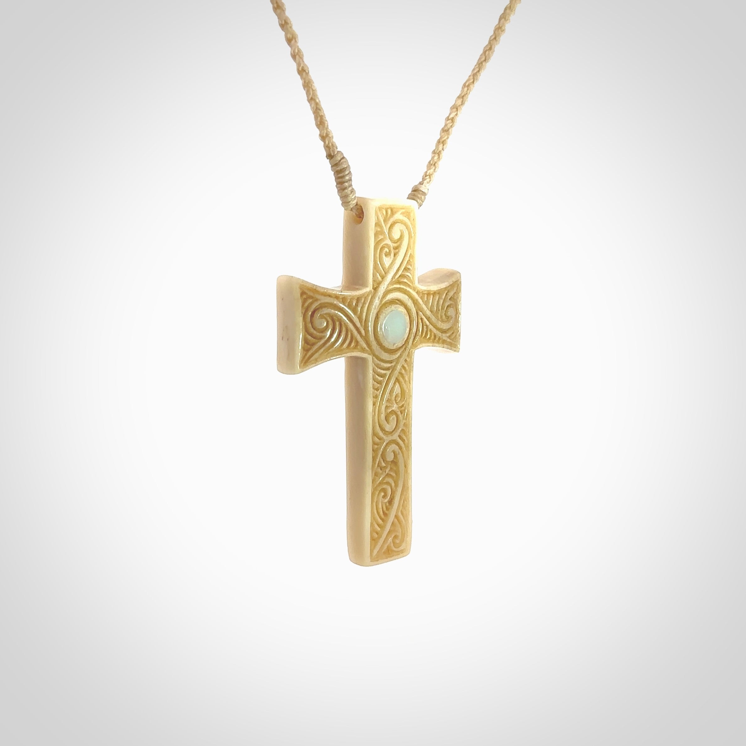 Hand carved Bone religious cross pendant by Andrew Doughty. Cross pendant with Opal inlay by Andrew Doughty with engraving in it. Beautiful unisex necklace hand carved in New Zealand, delivered in a woven kete pouch. Provided with an adjustable beige cord.