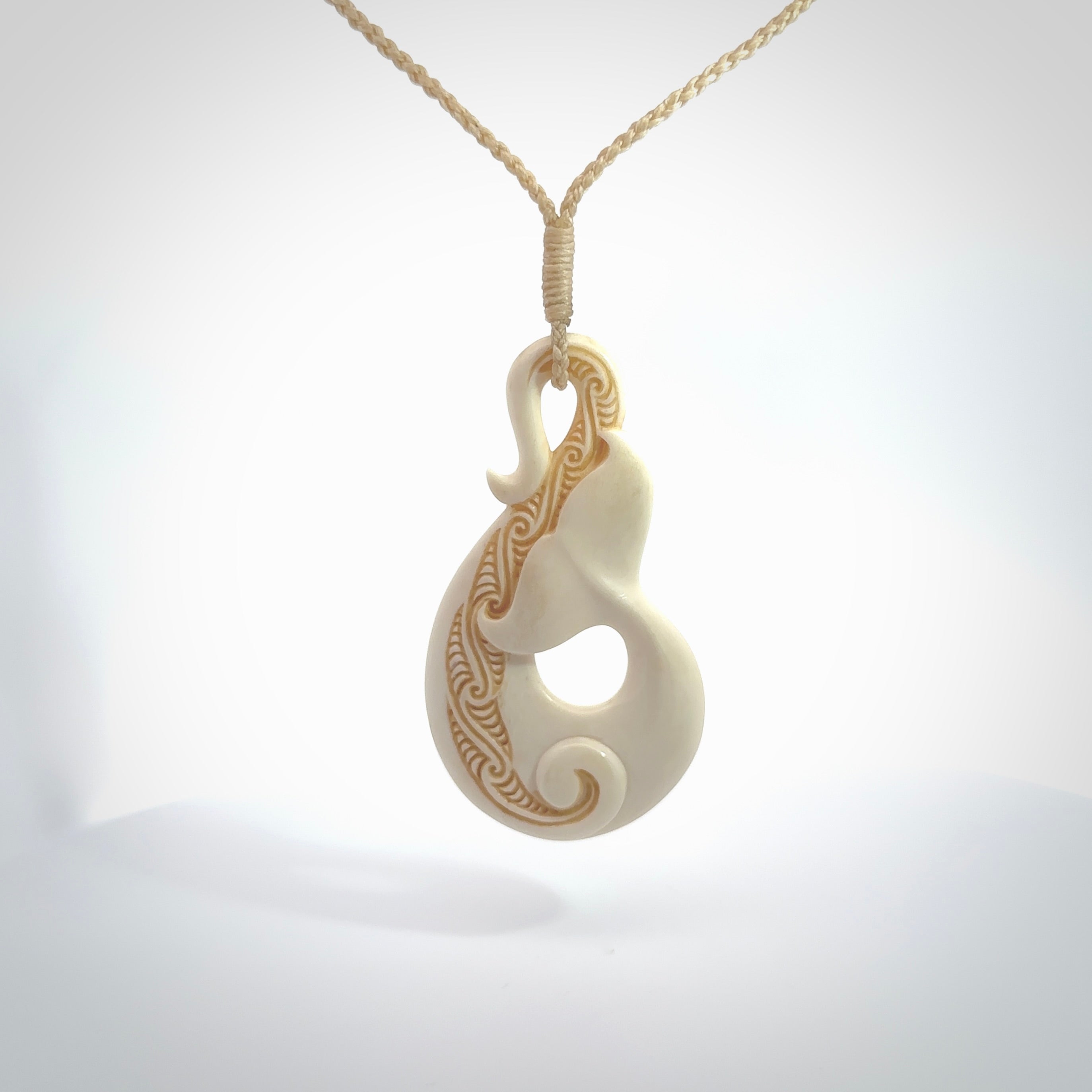 Hand carved Bone Whale Tail pendant by Andrew Doughty. Whale tail pendant by Andrew Doughty with engraving in it. Beautiful unisex necklace hand carved in New Zealand, delivered in a woven kete pouch. Provided with an adjustable beige cord.