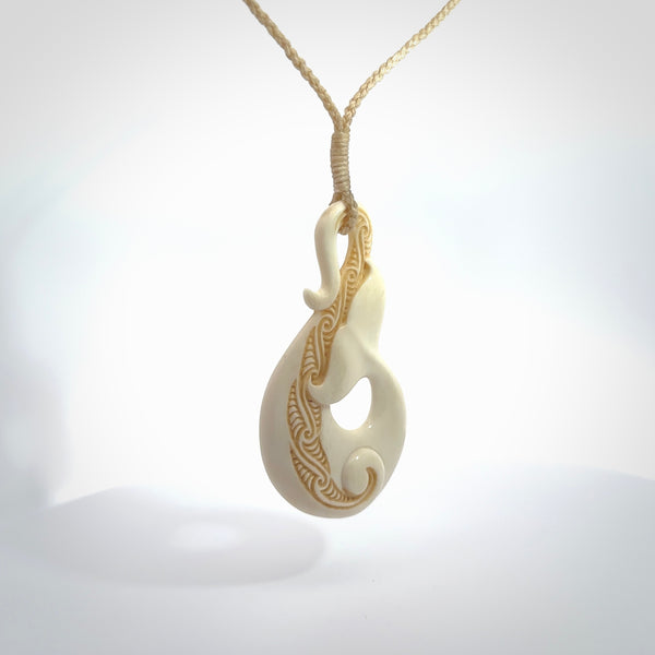 Hand carved Bone Whale Tail pendant by Andrew Doughty. Whale tail pendant by Andrew Doughty with engraving in it. Beautiful unisex necklace hand carved in New Zealand, delivered in a woven kete pouch. Provided with an adjustable beige cord.