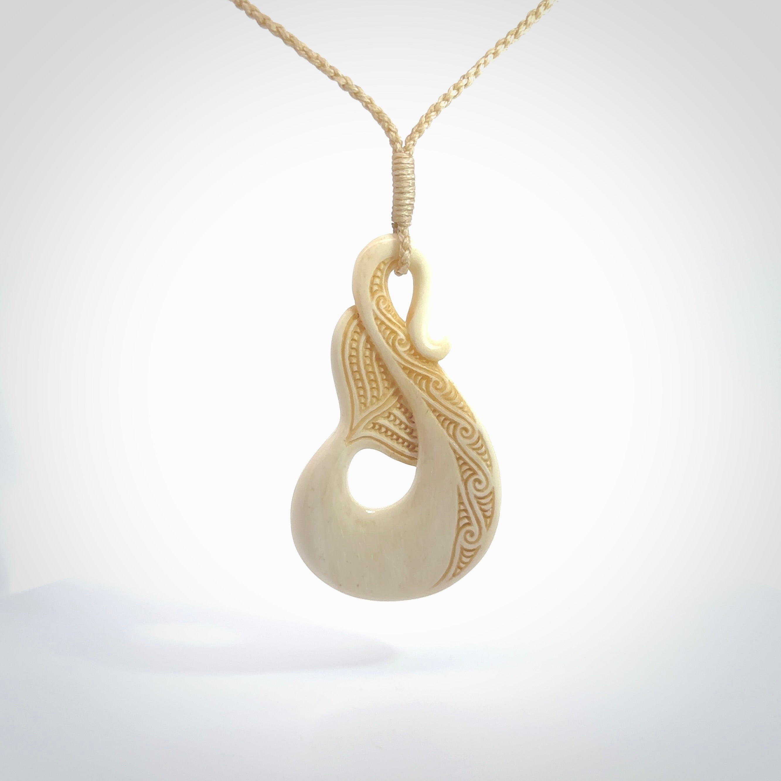 Hand carved Bone Whale Tail pendant by Andrew Doughty. Whale tail pendant by Andrew Doughty with engraving in it. Beautiful unisex necklace hand carved in New Zealand, delivered in a woven kete pouch. Provided with an adjustable beige cord.