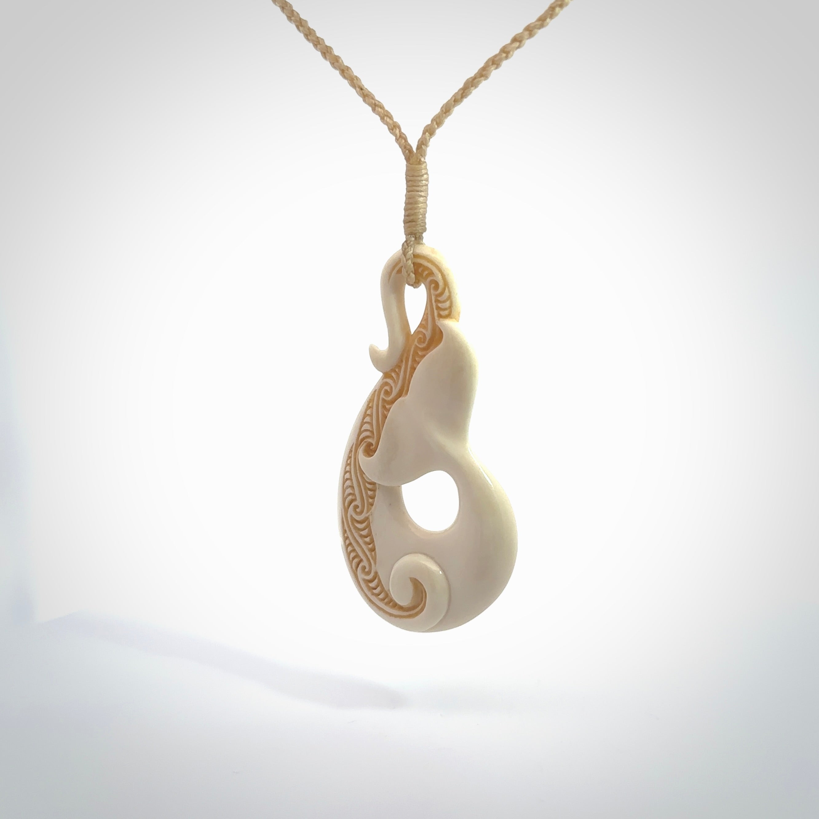 Hand carved Bone Whale Tail pendant by Andrew Doughty. Whale tail pendant by Andrew Doughty with engraving in it. Beautiful unisex necklace hand carved in New Zealand, delivered in a woven kete pouch. Provided with an adjustable beige cord.