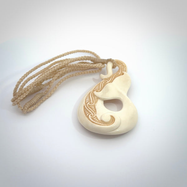 Hand carved Bone Whale Tail pendant by Andrew Doughty. Whale tail pendant by Andrew Doughty with engraving in it. Beautiful unisex necklace hand carved in New Zealand, delivered in a woven kete pouch. Provided with an adjustable beige cord.
