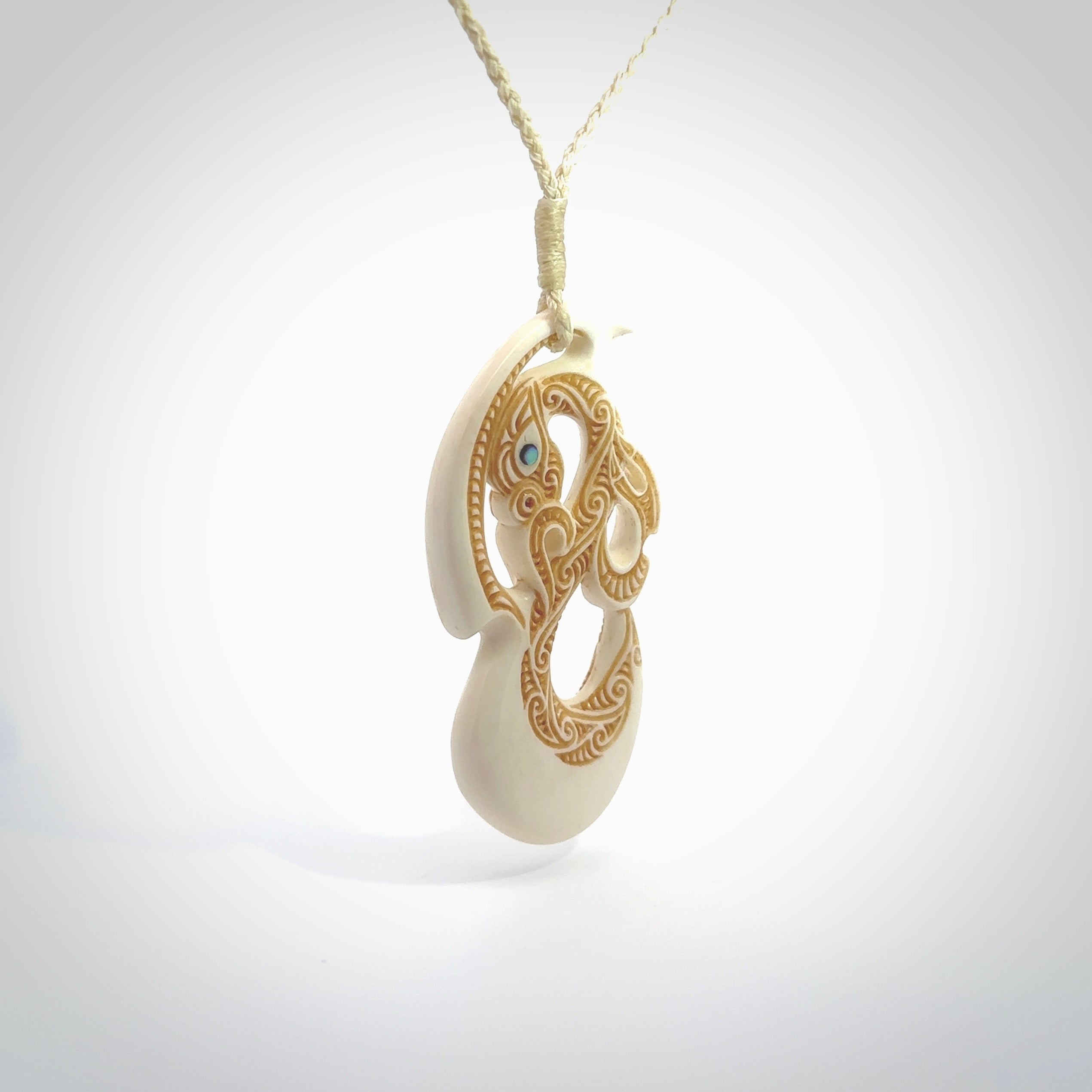 This picture shows a carved manaia in bone. The artist has carved traditional decorative kowhaiwhai designs into the body and these run up the insides of the manaia. These have specific meanings. It is provided with a hand-plaited beige cord that is length adjustable. Free shipping worldwide.